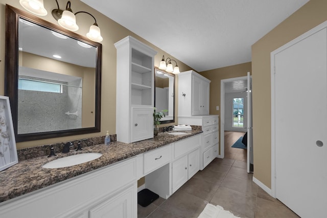 bathroom with double vanity, a sink, walk in shower, and tile patterned floors