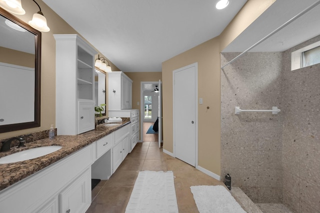 bathroom featuring double vanity, a sink, tile patterned floors, and tiled shower