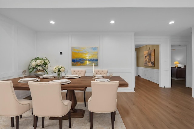 dining space featuring recessed lighting, light wood finished floors, and a decorative wall