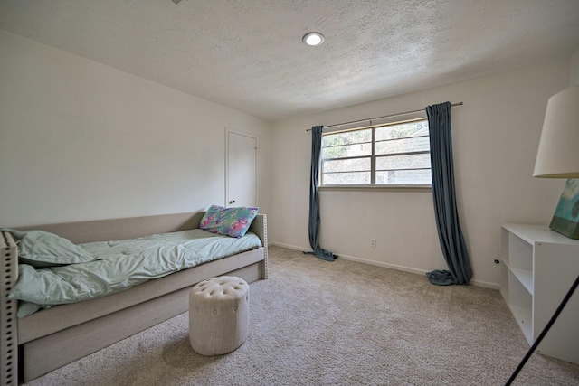 bedroom with baseboards, a textured ceiling, and light colored carpet