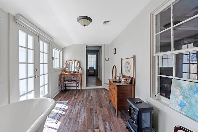 interior space featuring visible vents, a wood stove, lofted ceiling, dark wood-type flooring, and french doors