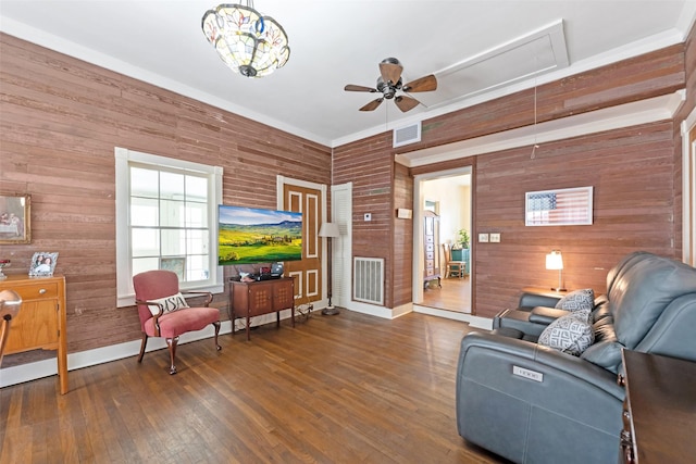 living room featuring ceiling fan, attic access, visible vents, wood-type flooring, and wooden walls