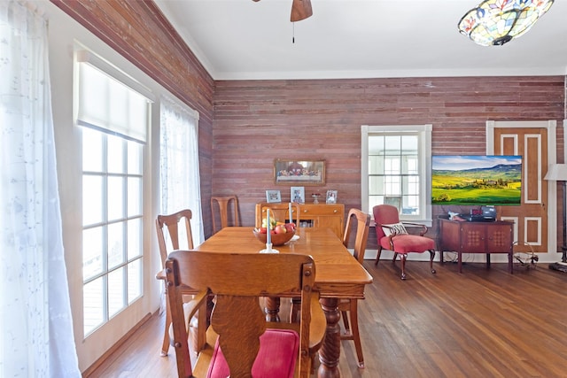 dining room with wooden walls, ceiling fan, and wood finished floors