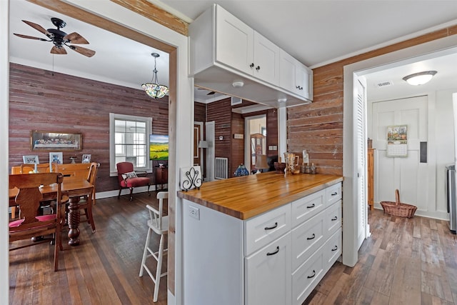 kitchen featuring white cabinetry, ceiling fan, wood walls, and dark wood-type flooring
