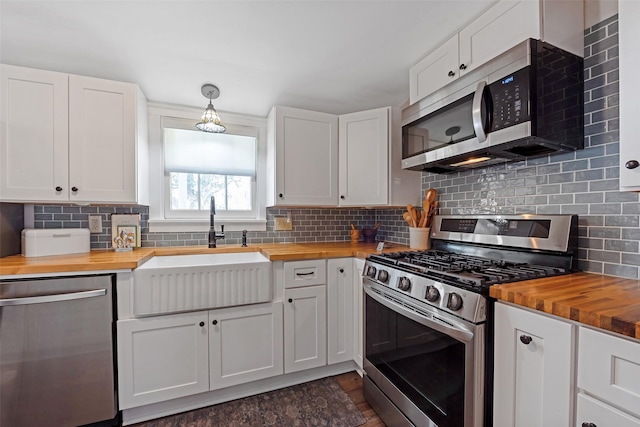 kitchen with decorative backsplash, stainless steel appliances, wooden counters, and a sink