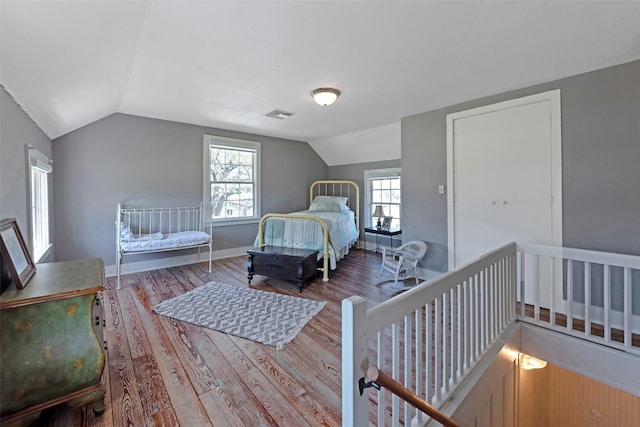 bedroom featuring visible vents, baseboards, wood finished floors, and vaulted ceiling
