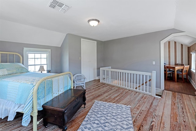 bedroom featuring baseboards, visible vents, wood finished floors, and vaulted ceiling