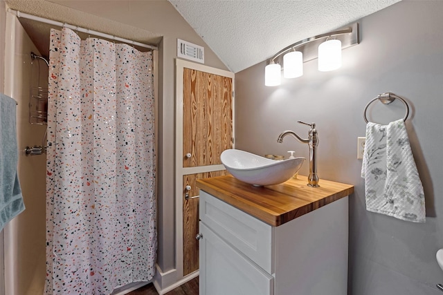 full bathroom featuring visible vents, vanity, lofted ceiling, curtained shower, and a textured ceiling