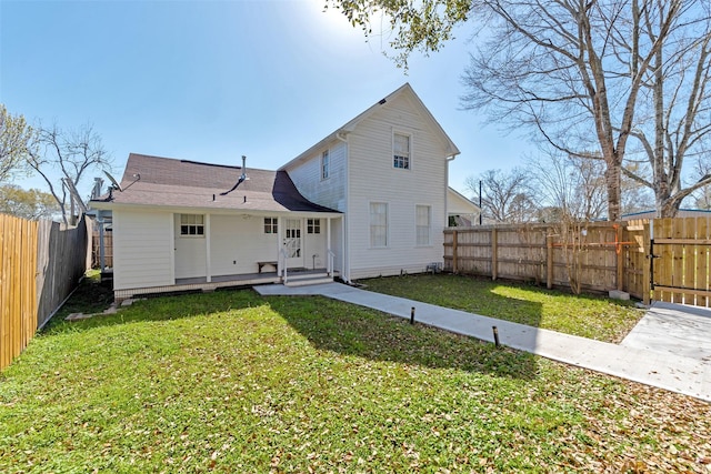 rear view of house featuring a lawn and a fenced backyard