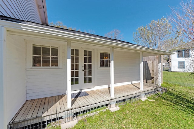 exterior space with a lawn, fence, french doors, and a wooden deck