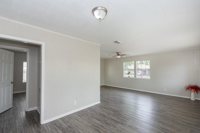 spare room featuring crown molding, ceiling fan, baseboards, dark wood-type flooring, and visible vents