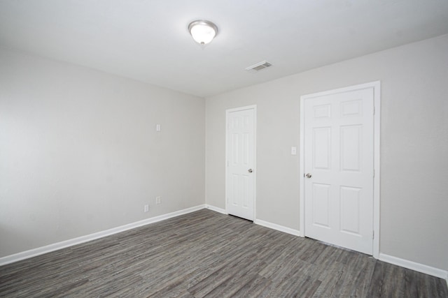 unfurnished bedroom with baseboards, visible vents, and dark wood-style floors