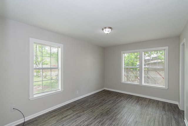 unfurnished room featuring baseboards and dark wood-style flooring