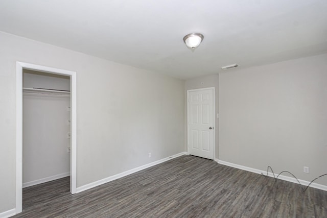 unfurnished bedroom with baseboards, visible vents, dark wood-style floors, and a closet