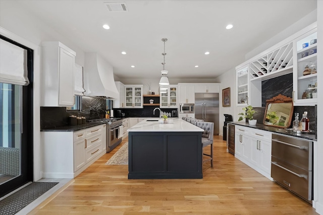 919 Worthshire St, Houston, TX 77008 - kitchen with built in appliances, premium range hood, a sink, light wood-style floors, and white cabinets