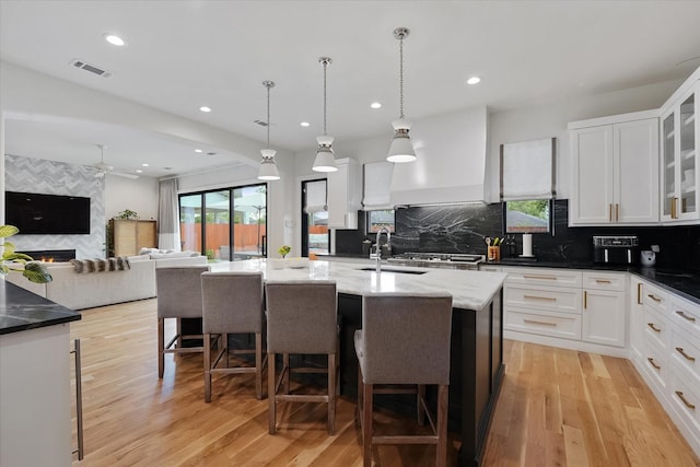 919 Worthshire St, Houston, TX 77008 - kitchen with a sink, light wood-type flooring, white cabinets, decorative backsplash, and a breakfast bar area