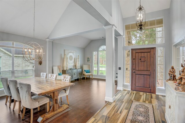 dining space with an inviting chandelier, high vaulted ceiling, ornate columns, and wood finished floors