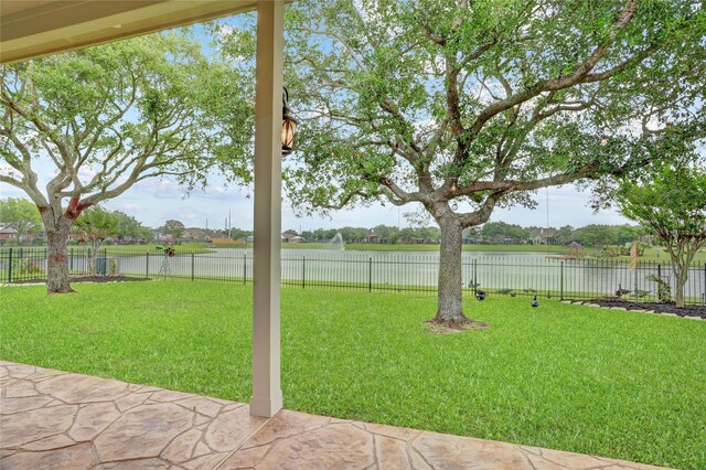 view of yard featuring a patio, a fenced backyard, and a water view