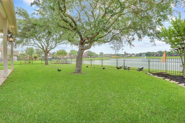 view of yard with a fenced backyard and a water view