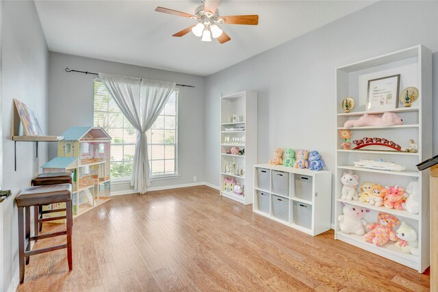 recreation room with baseboards, ceiling fan, and wood finished floors
