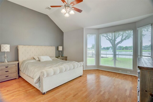 bedroom featuring a ceiling fan, visible vents, vaulted ceiling, baseboards, and light wood-style floors