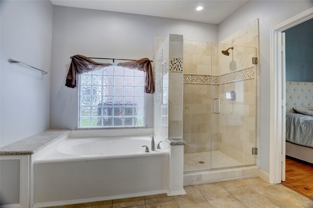 ensuite bathroom featuring connected bathroom, tile patterned floors, a shower stall, and a bath