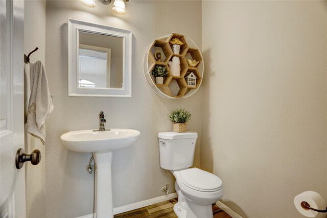 bathroom featuring baseboards, a sink, wood finished floors, and toilet