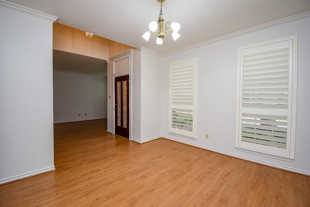 spare room with light wood-style floors, baseboards, crown molding, and a notable chandelier