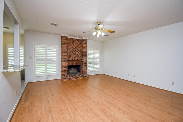 unfurnished living room featuring visible vents, a fireplace, baseboards, ceiling fan, and light wood-style flooring