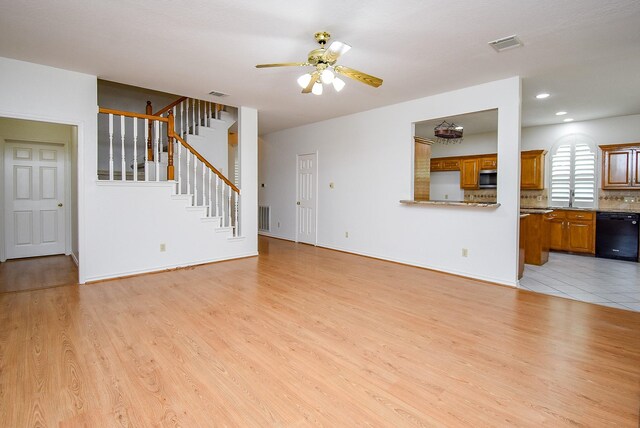 unfurnished living room featuring visible vents, a ceiling fan, light wood finished floors, and stairs