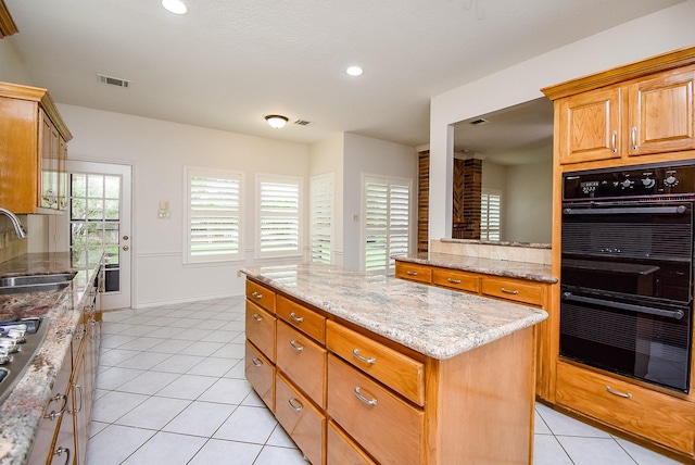 6007 Gideon Ct, Sugar Land, TX 77479 - kitchen featuring visible vents, dobule oven black, light tile patterned flooring, a center island, and a sink