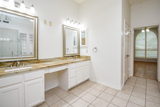 full bath featuring double vanity, a sink, a stall shower, and tile patterned floors