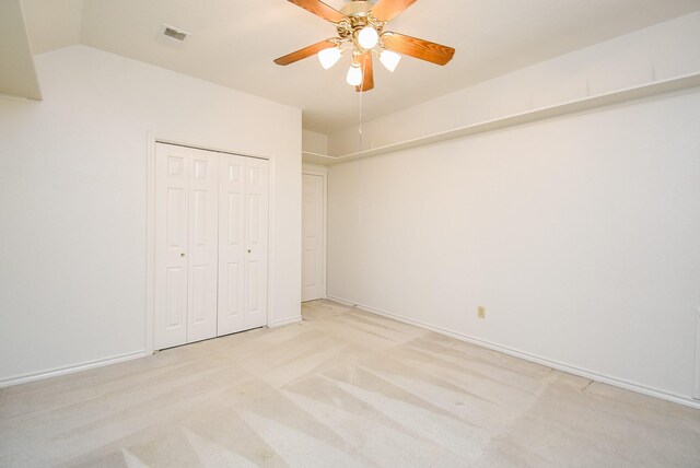 unfurnished bedroom featuring visible vents, a closet, light carpet, a ceiling fan, and vaulted ceiling