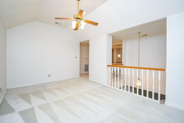 carpeted empty room with ceiling fan, visible vents, and lofted ceiling