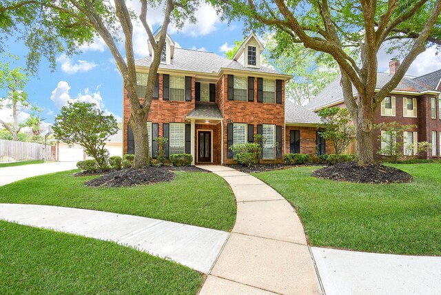 view of front facade featuring brick siding, fence, and a front yard