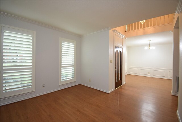 unfurnished room featuring baseboards, ornamental molding, wood finished floors, and a chandelier