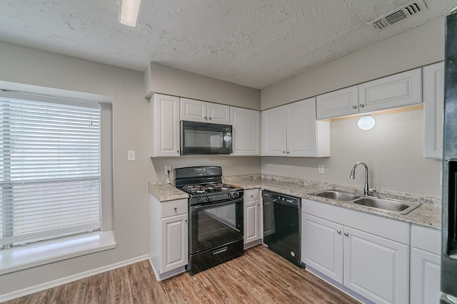20211 Big Timber Ct, Humble, TX 77346 - kitchen with black appliances, a sink, light wood finished floors, light countertops, and white cabinets