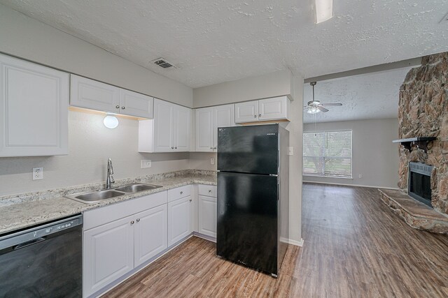 kitchen with light wood-style floors, a sink, a textured ceiling, and black appliances