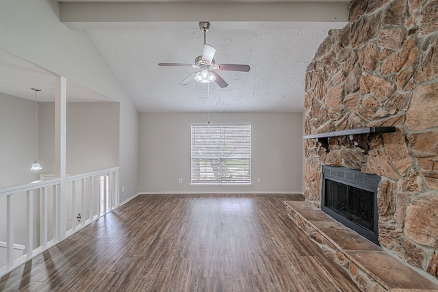 unfurnished living room featuring wood finished floors, a stone fireplace, vaulted ceiling with beams, a textured ceiling, and a ceiling fan