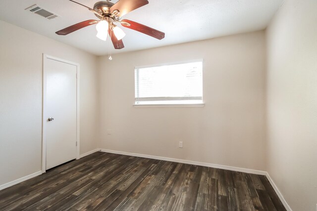 empty room with a ceiling fan, baseboards, visible vents, and dark wood finished floors
