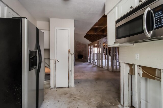 kitchen featuring white cabinets, stainless steel appliances, and unfinished concrete flooring