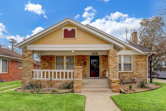 1106 Key St, Houston, TX 77009 - view of front facade featuring a chimney, a front yard, brick siding, and a porch