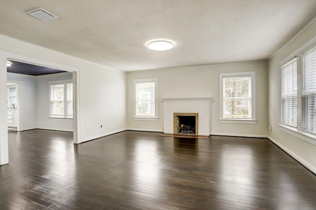 1106 Key St, Houston, TX 77009 - unfurnished living room featuring dark wood finished floors, healthy amount of natural light, a fireplace with flush hearth, a textured ceiling, and baseboards