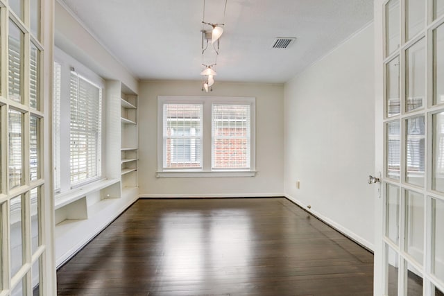 1106 Key St, Houston, TX 77009 - unfurnished dining area featuring dark wood-type flooring, crown molding, built in shelves, and baseboards