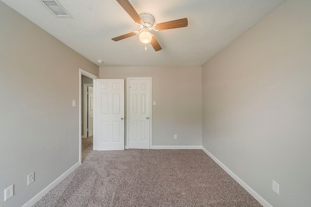 unfurnished bedroom featuring baseboards, ceiling fan, carpet, and visible vents