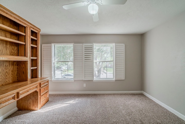 unfurnished office with a ceiling fan, baseboards, carpet, and a textured ceiling