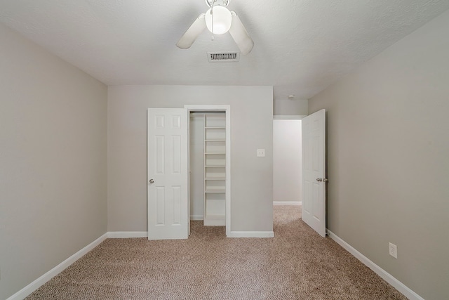 unfurnished bedroom featuring a ceiling fan, visible vents, baseboards, a closet, and light carpet