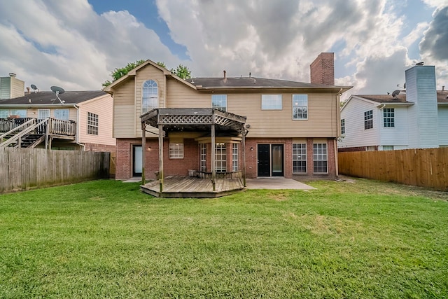 rear view of property with a yard, brick siding, a wooden deck, and a fenced backyard