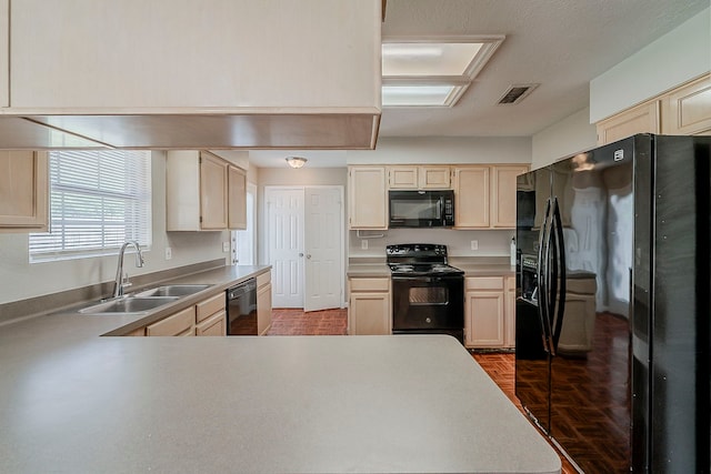 kitchen featuring a sink, light countertops, a peninsula, visible vents, and black appliances