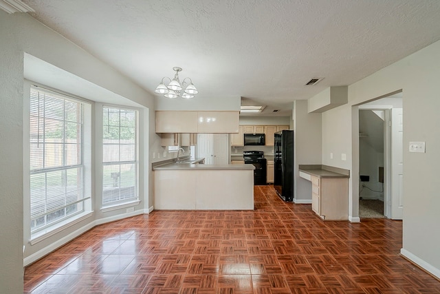 kitchen featuring a peninsula, baseboards, a healthy amount of sunlight, and black appliances